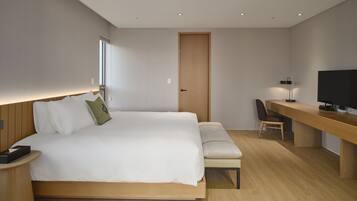 Una habitación de hotel moderna con una cama grande, una mesita de noche y un escritorio con una silla.