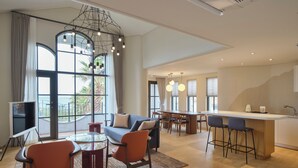 Una habitación de hotel moderna con sofá, mesa de comedor, sillas y una zona de cocina.