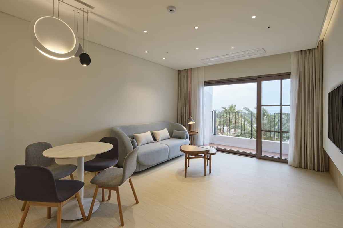 A modern living room with a sofa, chairs, a round table, and a large window with a view.