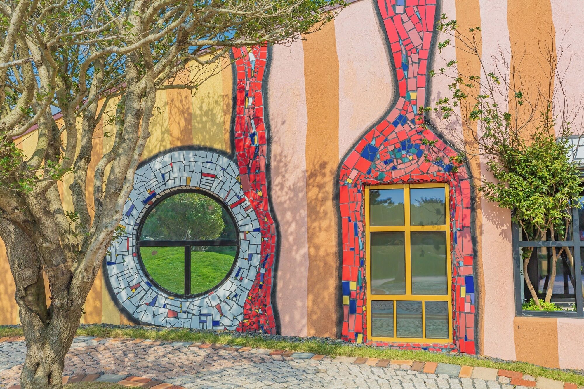 Un edificio con una fachada de mosaico único, una ventana circular y una puerta amarilla.