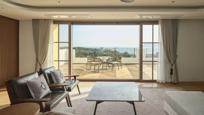 A spacious living room with a large sliding glass door leading to an outdoor terrace. - Hundert Hills (Jeju City)