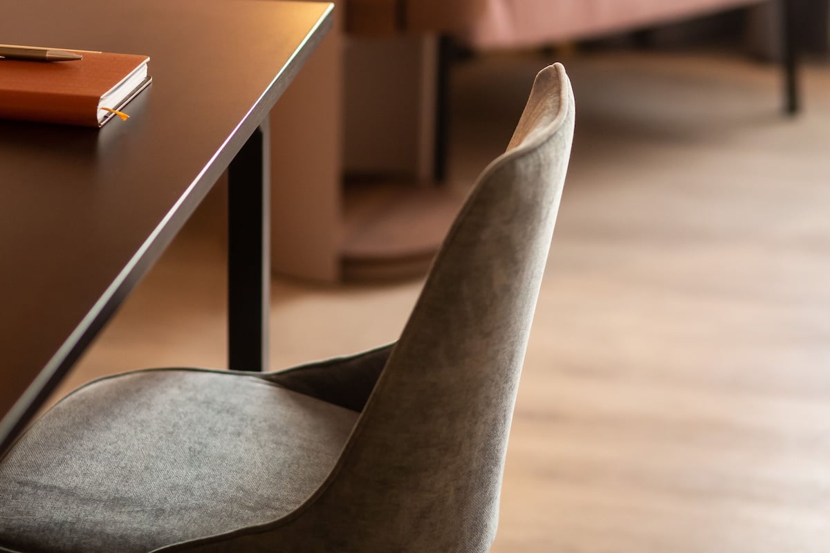 A modern interior with a wooden table, a grey upholstered chair, and a pink sofa.