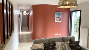 A hallway with a sofa and pillows, a hanging light fixture, and a framed picture on the wall.