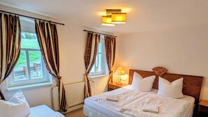 A hotel room with two beds, a window with curtains, a bedside lamp, and a headboard.