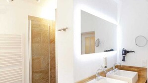 A bathroom with a shower, two sinks, a mirror, and a hairdryer.