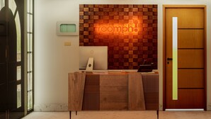 Vastaanottotiski, jossa on puupaneelista tehty koristelu ja neonvalokyltti, jossa lukee: ”roomph!”.