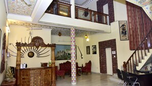 A spacious lobby with a high ceiling, a central column, and a staircase leading to an upper level.