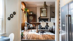 A dining area with a wooden table, white chairs, a cowhide rug, and a rustic fireplace.
