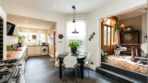 A modern kitchen with a dining area, a washing machine, and a dining table with chairs.