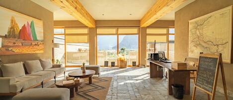 A spacious living area with a sofa, coffee table, and a view of the mountains through large windows.