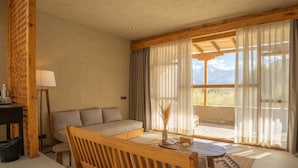 Una stanza con divano, un tavolo di legno e vista sulle montagne attraverso ampie finestre.