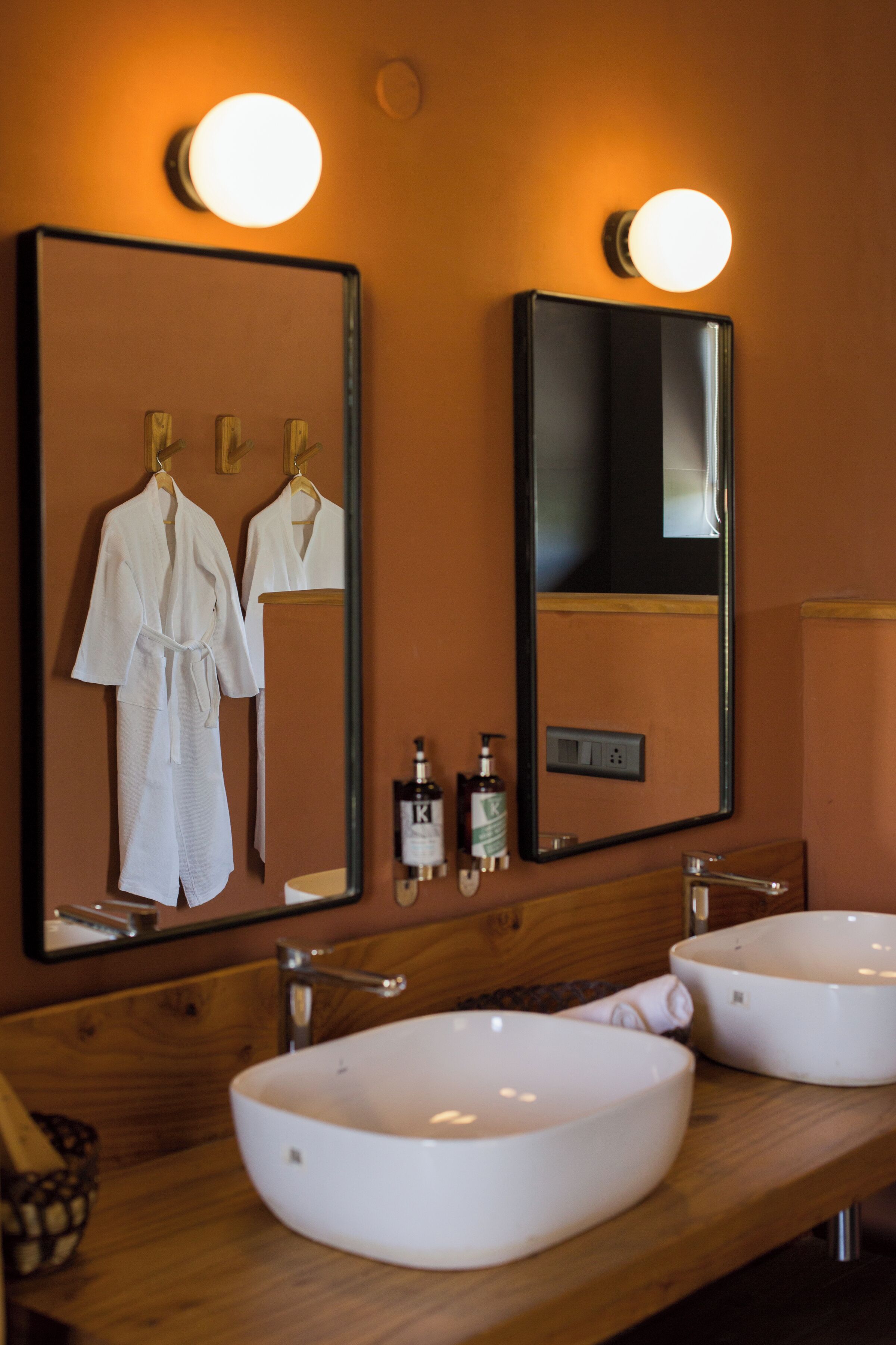 A bathroom with two sinks, a mirror, and a robe rack.
