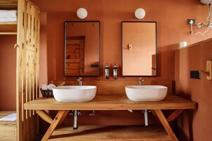 Un baño con dos lavamanos, tocador de madera y espejos.