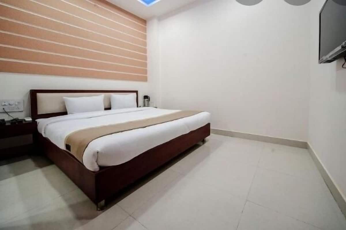 A bedroom with a bed, nightstand, and a TV mounted on the wall.