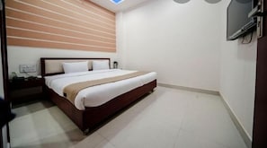 A bedroom with a bed, nightstand, and a TV mounted on the wall. - Hotel Durga Silverline (Jodhpur)