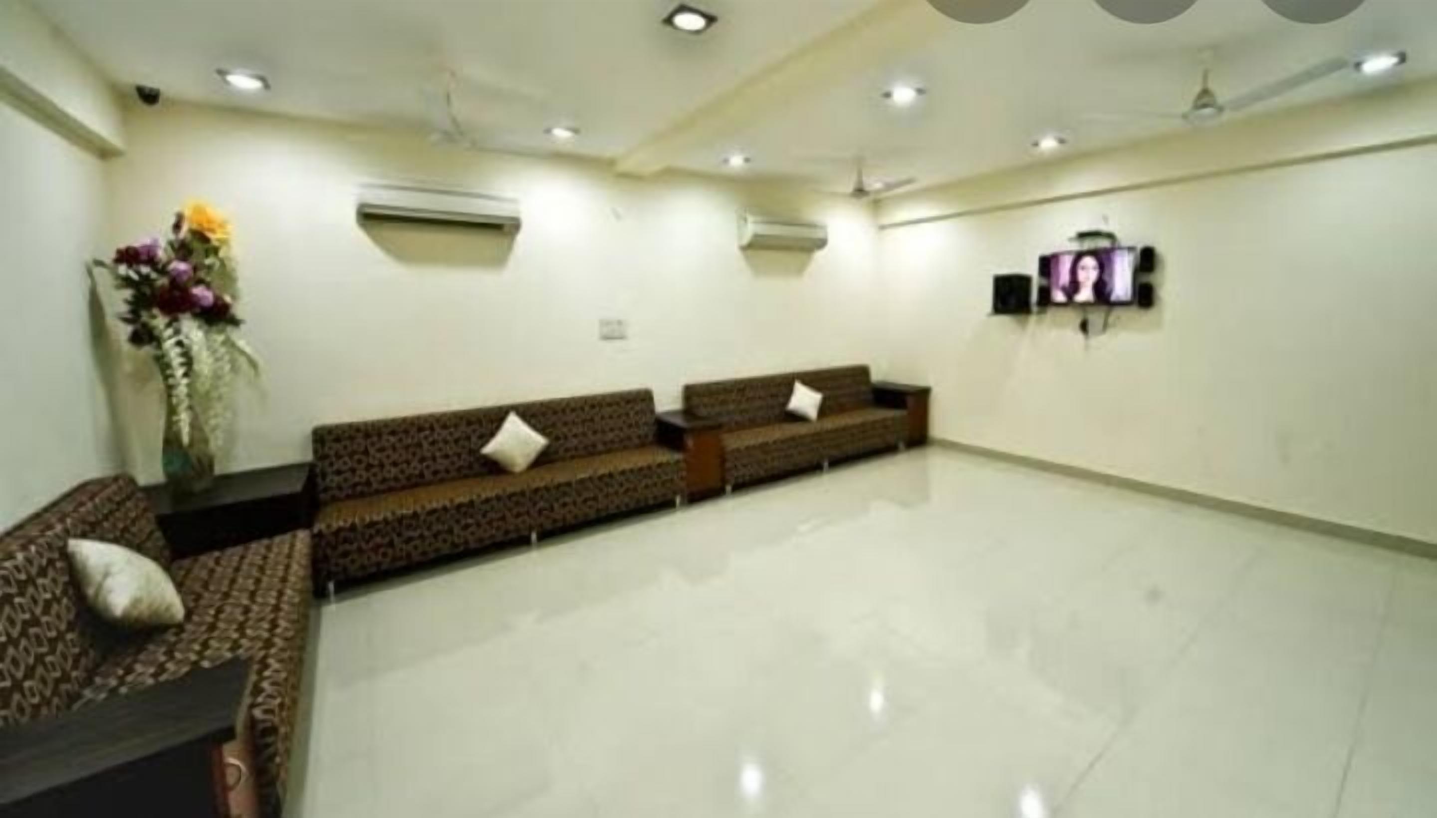 A spacious room with two sofas, a small table, and a wall-mounted TV.