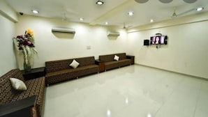 A spacious room with two sofas, a small table, and a wall-mounted TV. - Hotel Durga Silverline (Jodhpur)