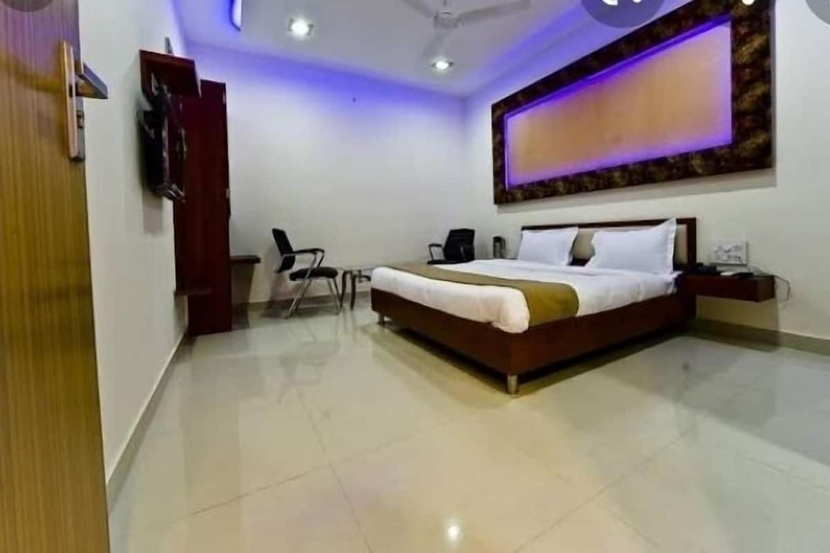 A bedroom with a bed, a desk, a chair, and a ceiling fan.