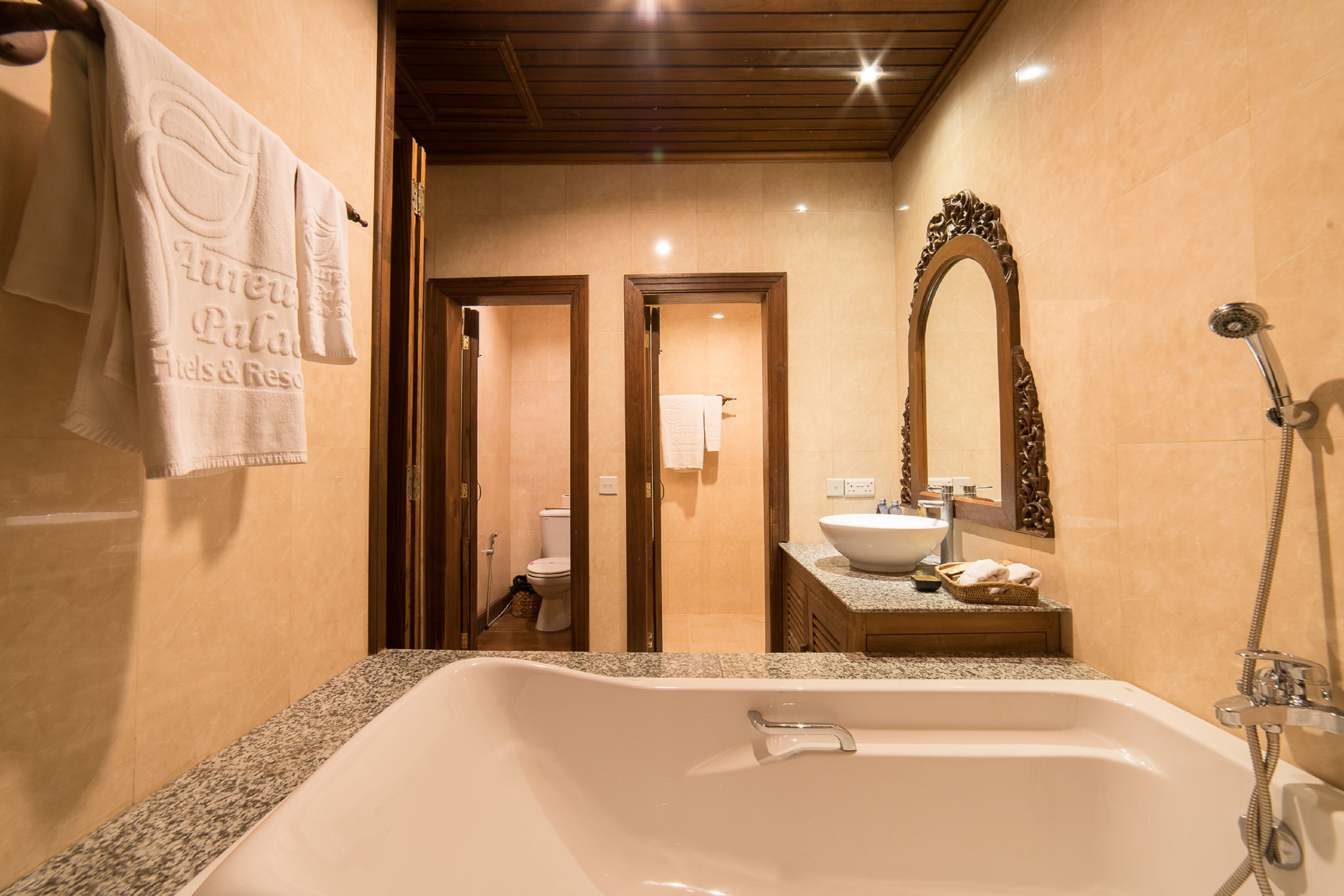 Un baño con una bañera grande, un lavamanos y un espejo.