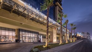 A hotel with a modern facade, large windows, and palm trees in front. - Citadines Abha (Abha)