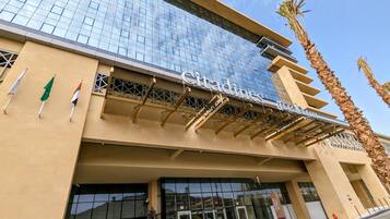 A hotel entrance with a glass facade, a name sign, and flags.