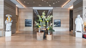 A modern lobby with wooden flooring, a central floral arrangement, and two statues on either side. - Citadines Abha (Abha)