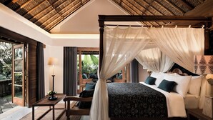 A bedroom with a canopy bed, a wooden table, and a view of the outdoors. - Kharista Villas & Retreat by Ekosistem (Canggu)