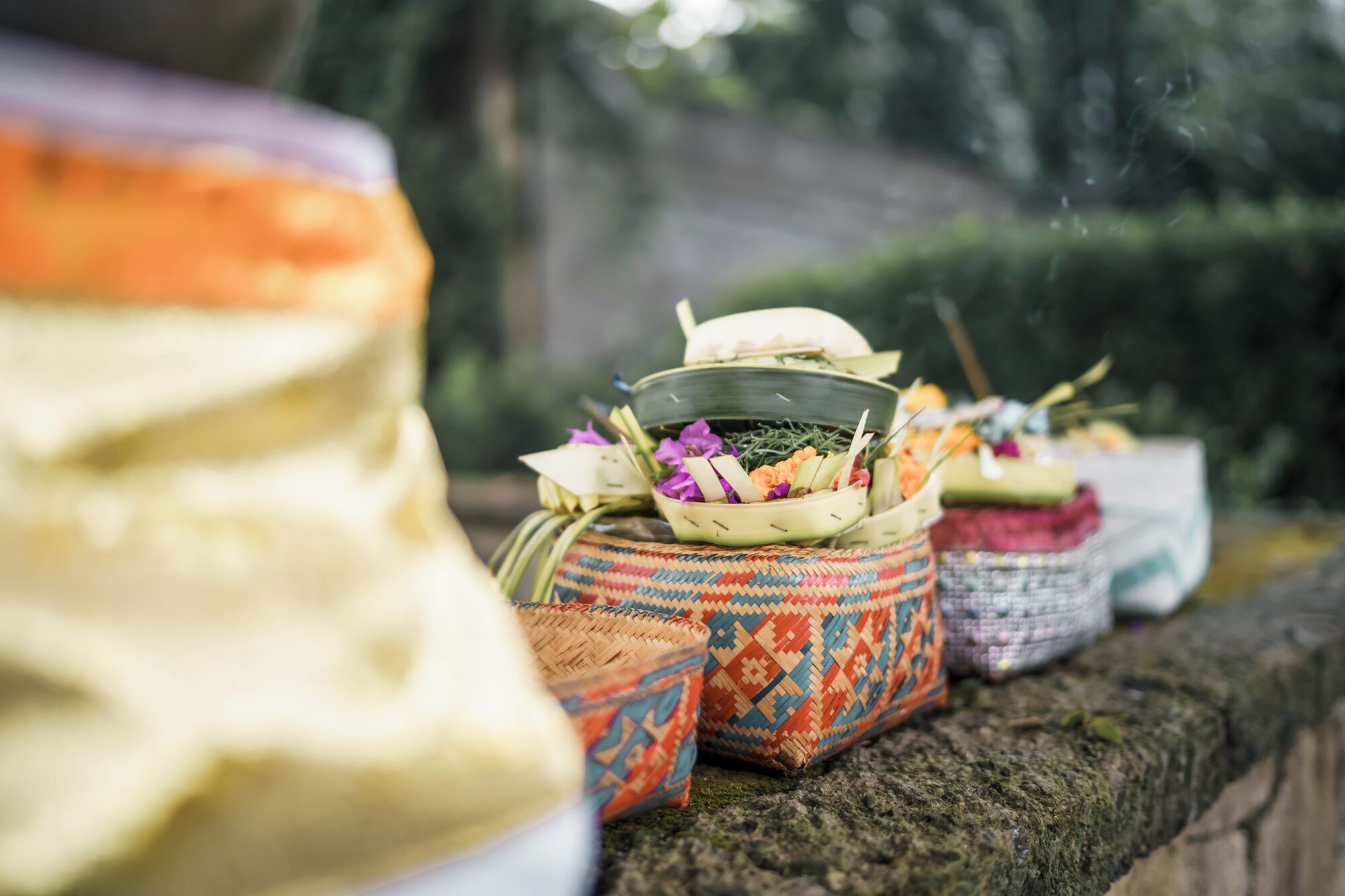 A variety of traditional woven baskets and containers, some with colorful patterns, placed on a stone surface.