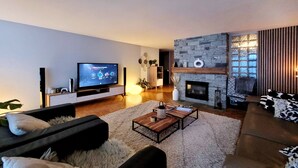 Una sala de estar moderna con un televisor de pantalla plana, una chimenea de piedra y un sofá.