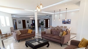 Ein geräumiger Wohnbereich mit zwei Sofas, einem Couchtisch und Pendelleuchten.