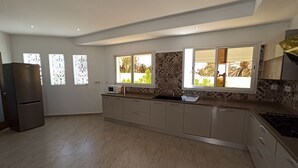 Eine moderne Küche mit Einbauofen, Mikrowelle und Spüle. Drei Fenster sorgen für natürliches Licht.