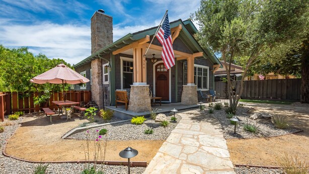 Ein Haus mit einer Steinterrasse, Sitzgelegenheiten im Freien und einer amerikanischen Flagge.