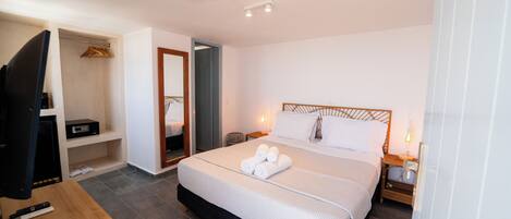 A hotel room with a bed, a TV, a desk with a remote control, and a wardrobe.