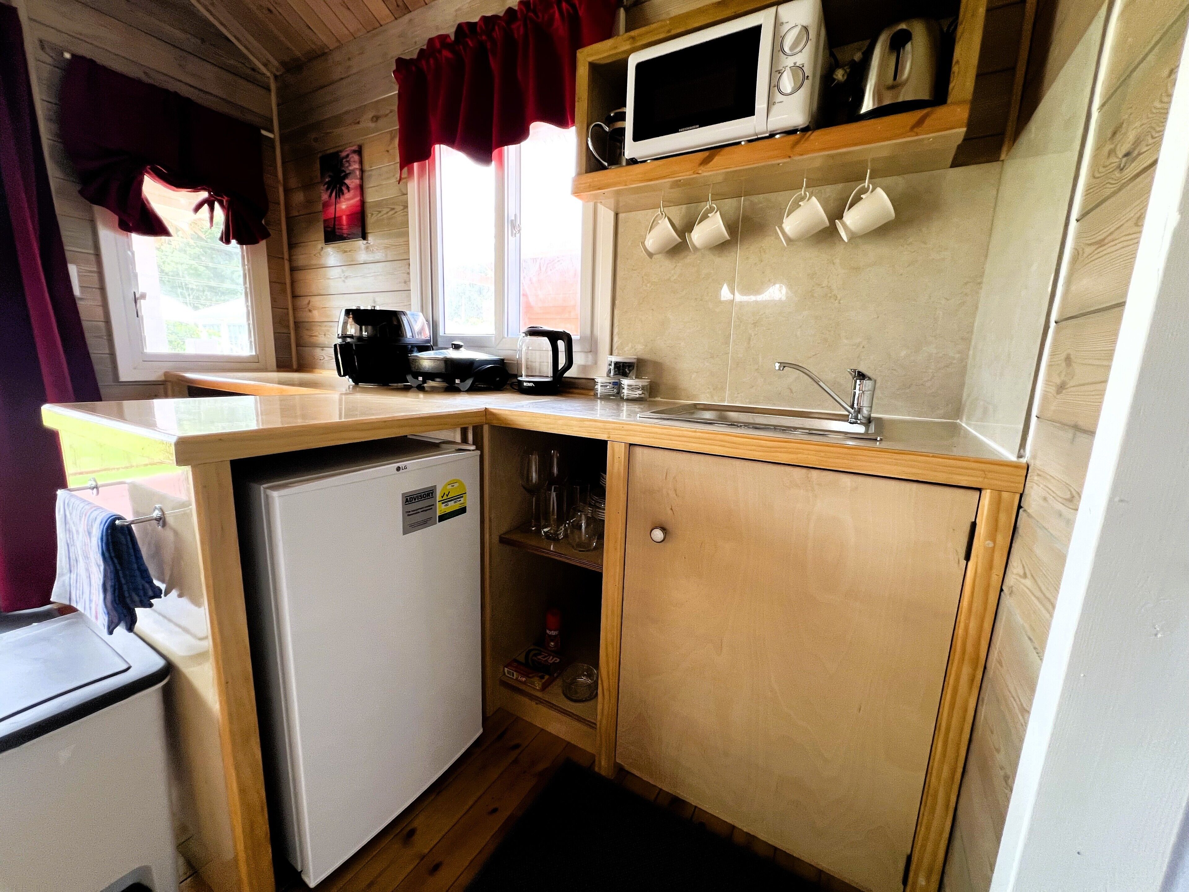 A compact kitchen with a microwave, sink, and a small refrigerator.