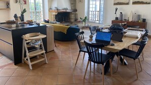 Un vaste espace de vie comprenant une cuisine, une table à manger et une cheminée.