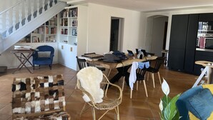 Un grand espace de vie comprenant un escalier, une bibliothèque, une table à manger avec des chaises et un coin cuisine.