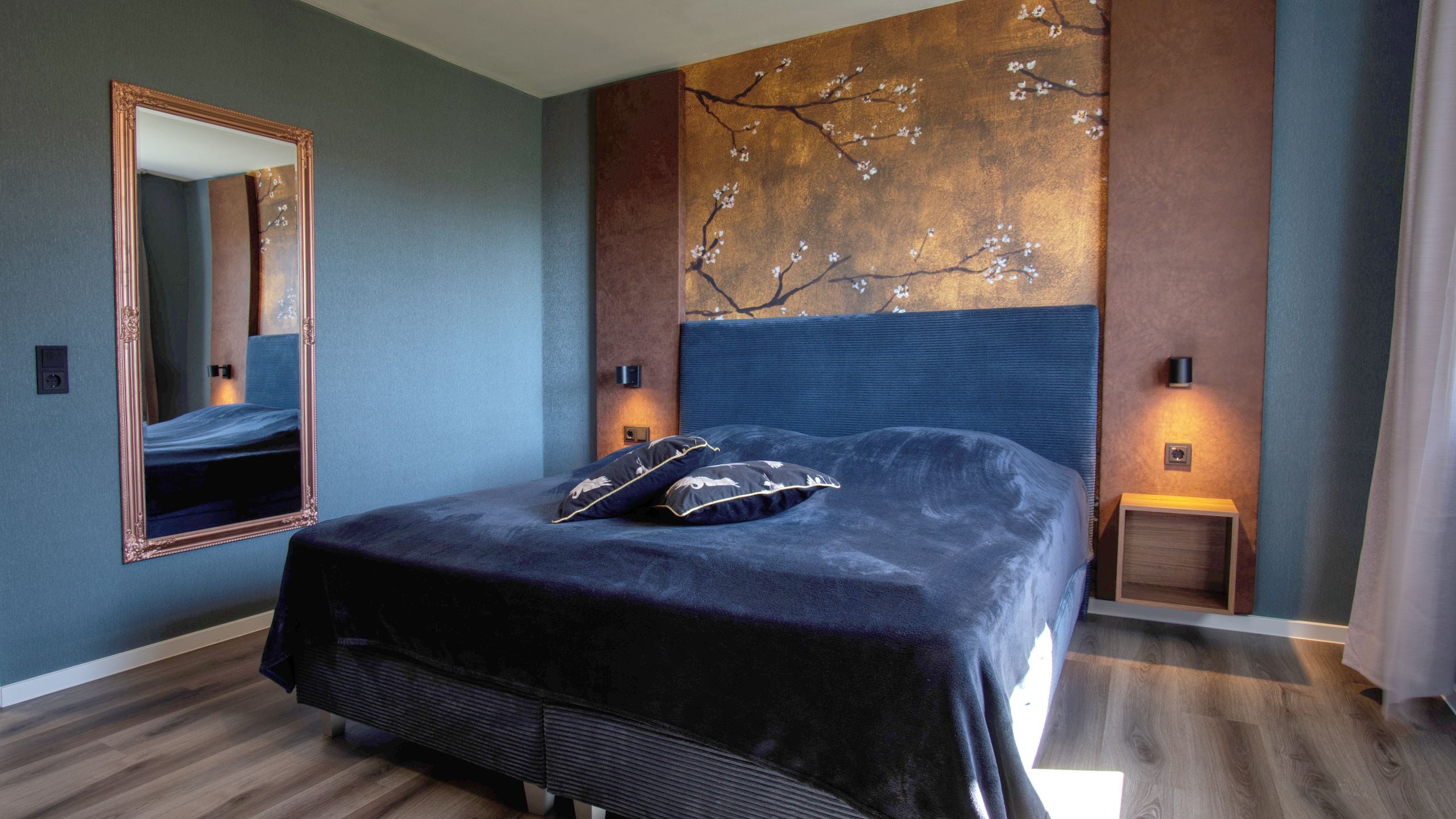 A bedroom with a large bed, a mirror, and a wall-mounted artwork.