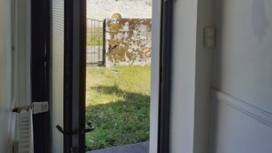 Een doorgang naar een binnenplaats met een stenen muur en een uitzicht op een kasteelachtig gebouw.