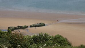 A beach with large rocks and a few people walking. - Villa Juno (Saint-Aubin-sur-Mer)