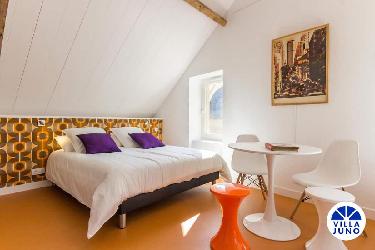 A modern bedroom with a bed, a small table, and a chair.