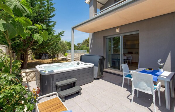 A patio with a hot tub, outdoor seating, and a view of the house.