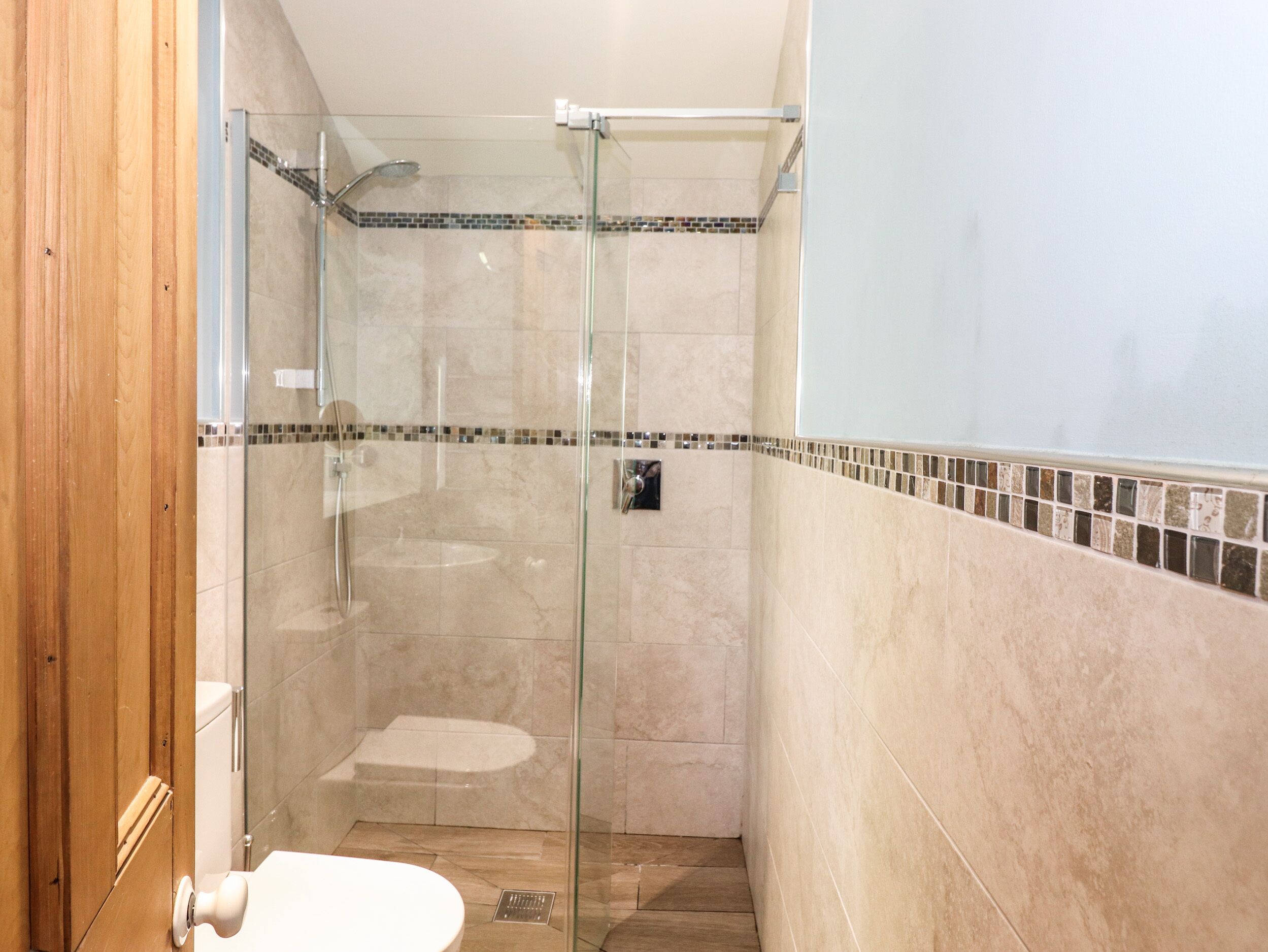 A modern bathroom with a glass-enclosed shower, a toilet, and a sink.