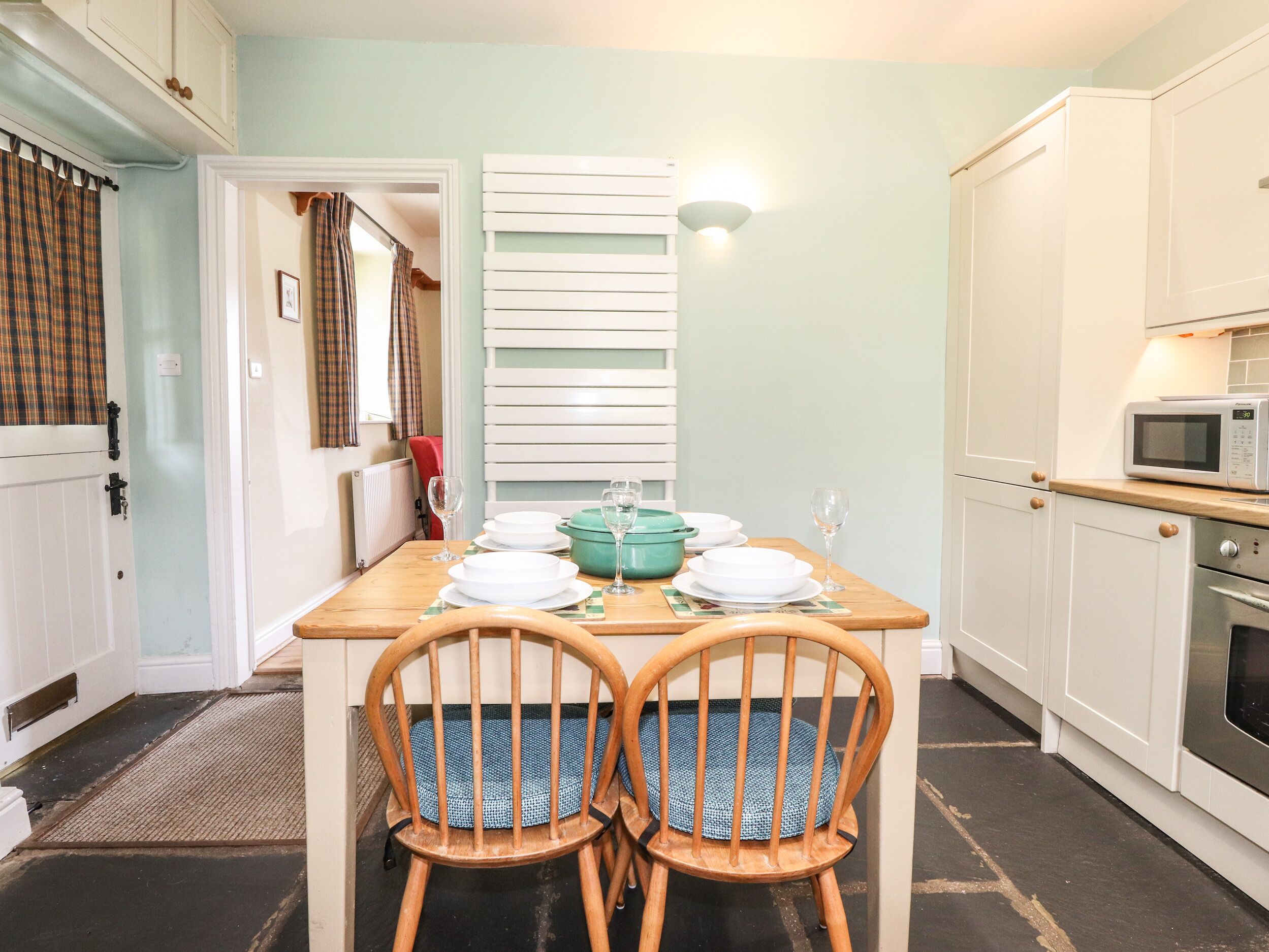 A kitchen with a dining table set for two, a microwave, and a stove.