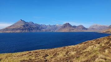 A coastal landscape with a prominent mountain range and a clear blue sea.