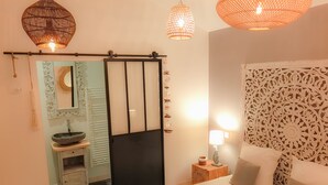 Une chambre à coucher comprenant un lit, une table de chevet avec une lampe, une tête de lit décorative et une porte coulissante.