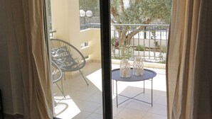 A balcony with a chair, a small table, and two glass candle holders.