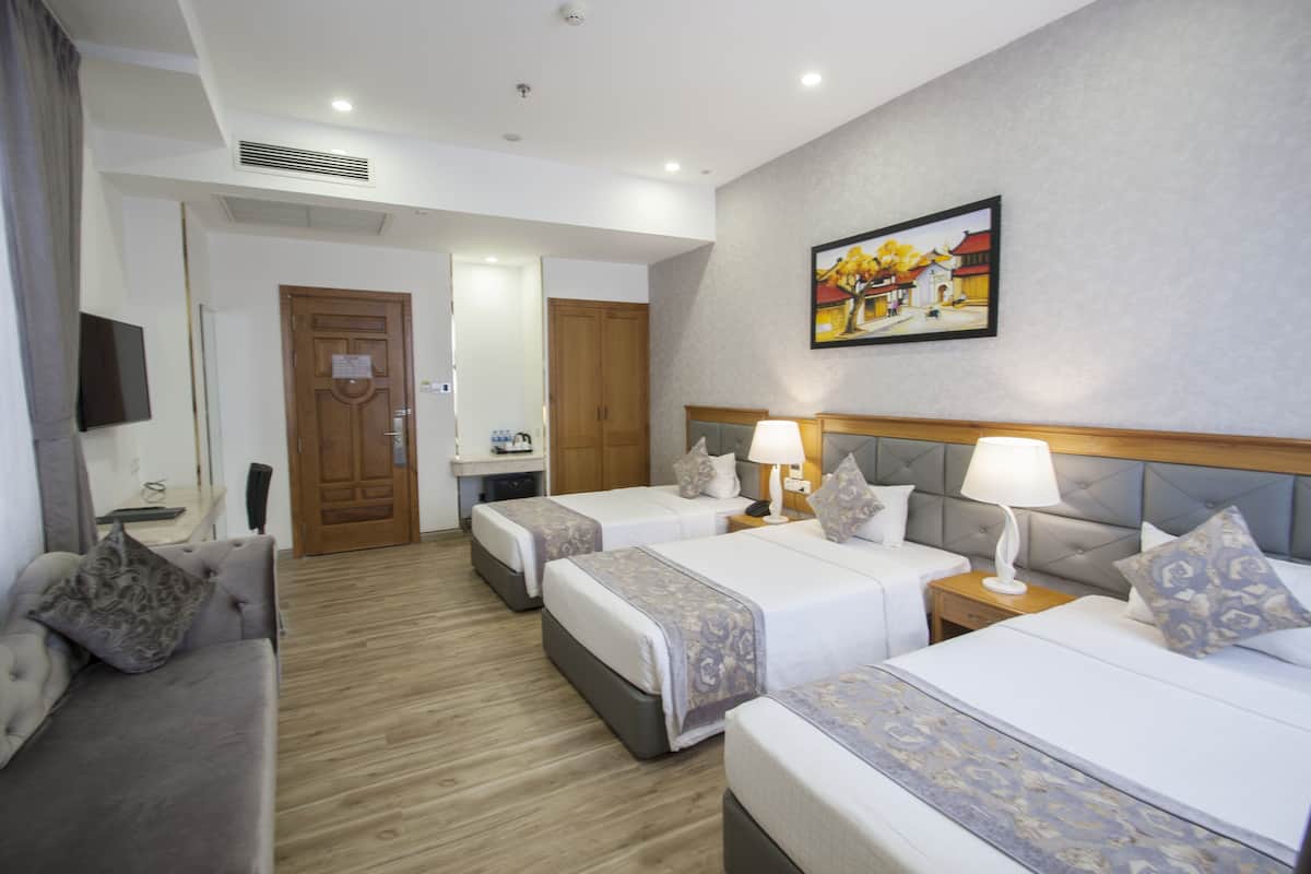 Habitación de hotel con dos camas, un sofá, un televisor y un cuadro en la pared.