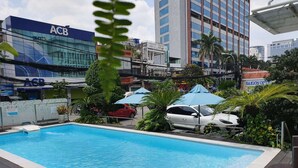 A swimming pool with a view of surrounding buildings, including an ACB bank and a Saigon Optic store. - Acnos Grand Hotel (Ho Chi Minh City)