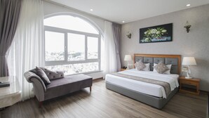 A modern bedroom with a large bed, a sofa, a nightstand, and a window with curtains. - Acnos Grand Hotel (Ho Chi Minh City)