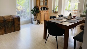 A dining area with a wooden table, black chairs, and a large window with a view of greenery. - Holiday rental Kallenbachtal I (Löhnberg)